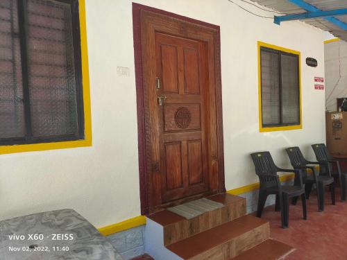 a room with a wooden door and some chairs at His Grace Camping at Malpe Beach in Udupi