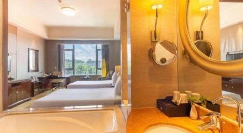 a bathroom with a sink and a mirror and a bed at Quanzhou Guest House Hotel in Quanzhou