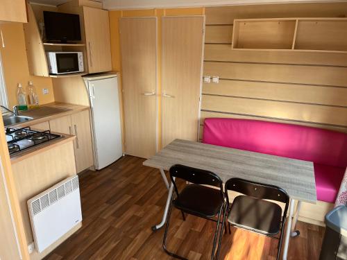a small kitchen with a table and two chairs at Camping De Collignon in Cherbourg en Cotentin
