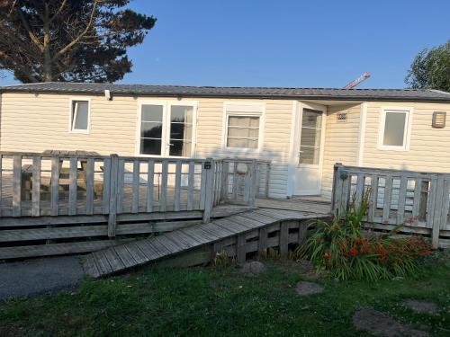 a house with a wooden porch and a fence at Camping De Collignon in Cherbourg en Cotentin