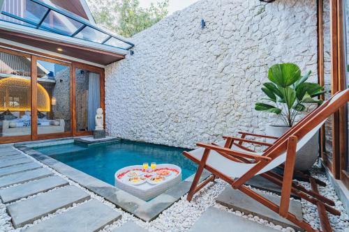 einen Pool mit einer Bank und einem Stuhl in der Unterkunft iRini Villas in Nusa Dua