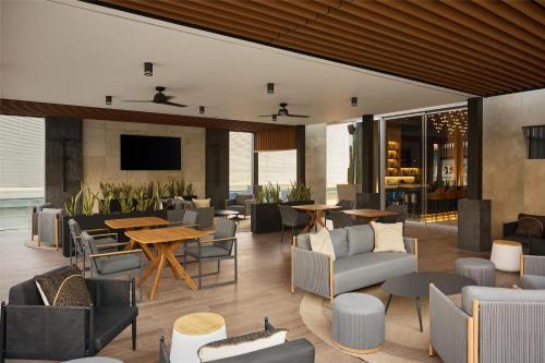 a lobby with couches and tables and a television at Hilton Garden Inn Chihuahua in Chihuahua