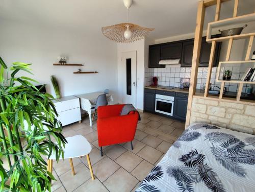 Il comprend un salon avec une chaise rouge et une cuisine. dans l'établissement Studio climatisé Résidence Le Galilée avec terrasse proche des remparts, à Avignon