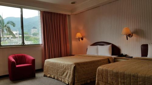 Empire Hotel في تايبيه: غرفة فندقية بسريرين وكرسي ونافذة