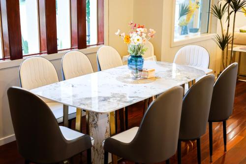a table with chairs and a vase of flowers on it at StayAU Pakenham Townhouse with Lakeview in Pakenham