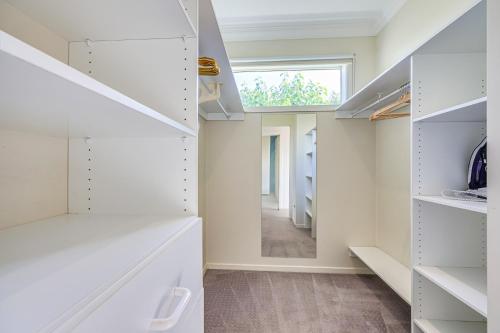 a dressing room with white shelves and a window at StayAU Pakenham Townhouse with Lakeview in Pakenham