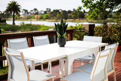 a white table and chairs with a potted plant on a deck at StayAU Pakenham Townhouse with Lakeview in Pakenham