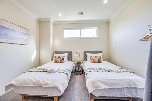 two twin beds in a room with a window at StayAU Pakenham Townhouse with Lakeview in Pakenham