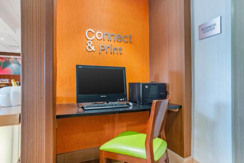 a desk with a computer and a green chair at Rodeway Inn in Pensacola