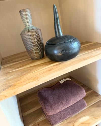 two vases and towels on a wooden shelf at La Playa Studios Hiriketiya in Hiriketiya