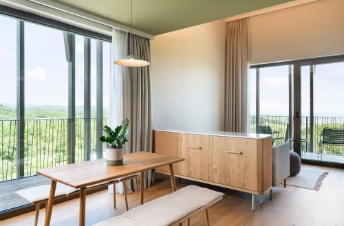 a living room with a table and large windows at WALDWEIT Rheingau Hotel und Retreat in Kiedrich