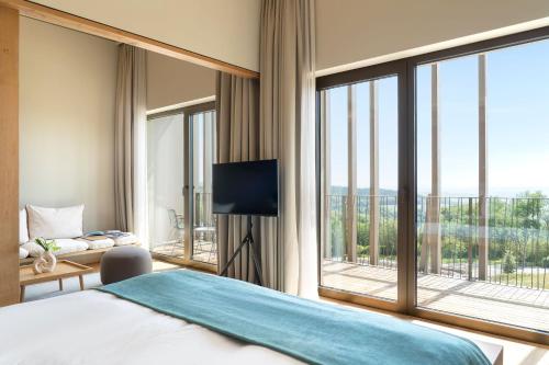 a bedroom with a large bed and a large window at WALDWEIT Rheingau Hotel und Retreat in Kiedrich