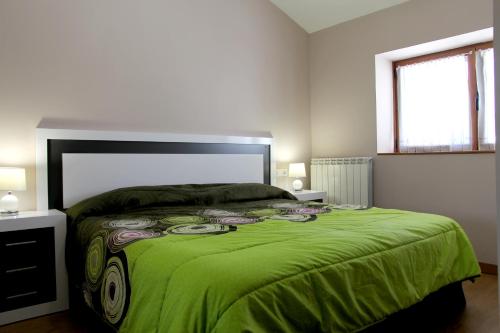 a bedroom with a large bed with a green blanket at Casa Rural Primorena Txiki in Linzoáin