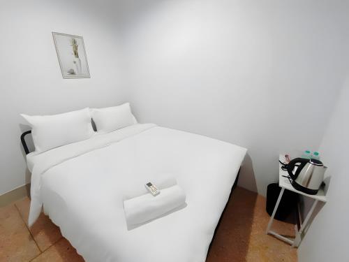 a white bed in a room with a table at The Hidden Khaosan เดอะ ฮิดเด้นข้าวสาร in Bang Bua Thong Railway Station