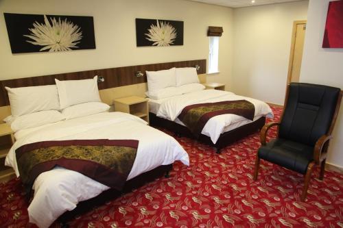 a hotel room with two beds and a chair at Cambridge Hotel in Huddersfield