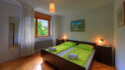 a bedroom with a bed with green sheets and a window at Guesthouse Marko in Bled