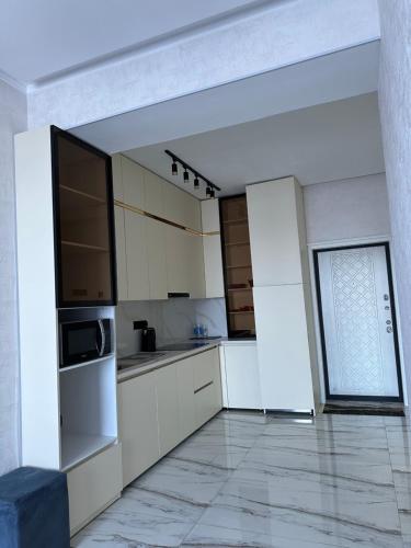 a kitchen with white cabinets and a large window at comfortable 1 bedroom apartment near centre of the city in Dushanbe