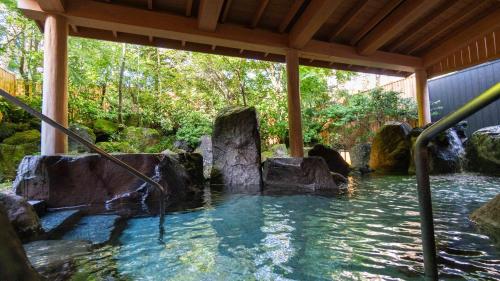 a plunge pool in a garden with rocks in the water at Motosu Phoenix Hotel in Fujikawaguchiko