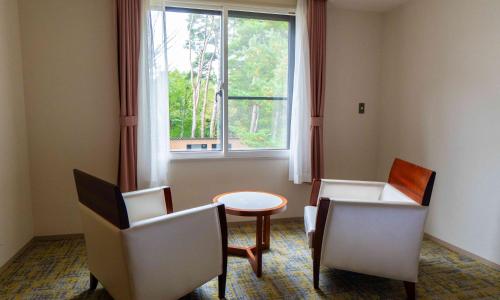 a room with a table and two chairs and a window at Motosu Phoenix Hotel in Fujikawaguchiko