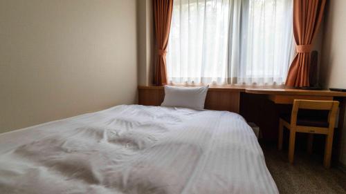 a white bed in a room with a window at Motosu Phoenix Hotel in Fujikawaguchiko