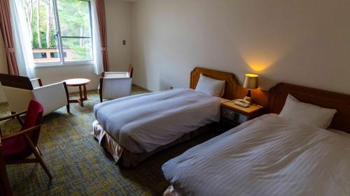 a hotel room with two beds and a table with a lamp at Motosu Phoenix Hotel in Fujikawaguchiko