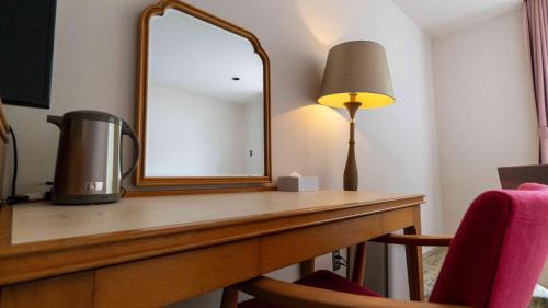 a desk with a mirror and a lamp on it at Motosu Phoenix Hotel in Fujikawaguchiko