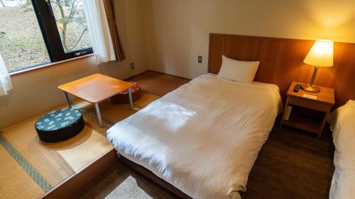 a bedroom with a large white bed and a window at Motosu Phoenix Hotel in Fujikawaguchiko