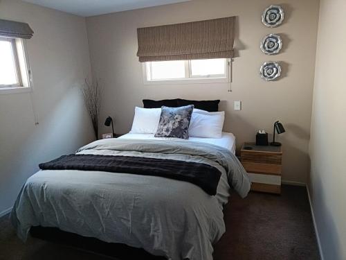 a bedroom with a large bed and two windows at Executive Hideaway in Christchurch
