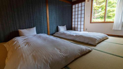 two twin beds in a room with a window at Motosu Phoenix Hotel in Fujikawaguchiko