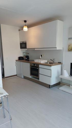 une cuisine avec des armoires blanches et un évier dans l'établissement Studio Le Trident de la mer - Axelle Loc'Appart, à Cannes