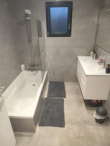 une salle de bain avec une baignoire blanche et un lavabo dans l'établissement Chambre spacieuse #1, à Clonas-sur-Varèze