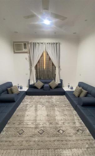 a living room with blue couches and a window at شقة الراحة والفخامة in Khamis Mushayt