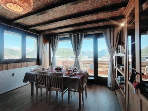 - une salle à manger avec une table, des chaises et de grandes fenêtres dans l'établissement Homency - Résidence Les Gémeaux A5, à L'Alpe-d'Huez