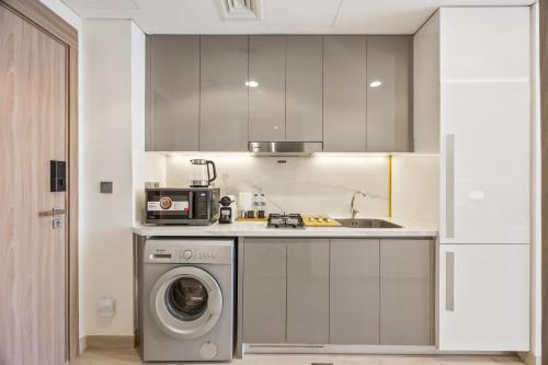 a kitchen with a washing machine and a sink at Elite Escape - Getaway in Azizi Riviera 13 in Dubai