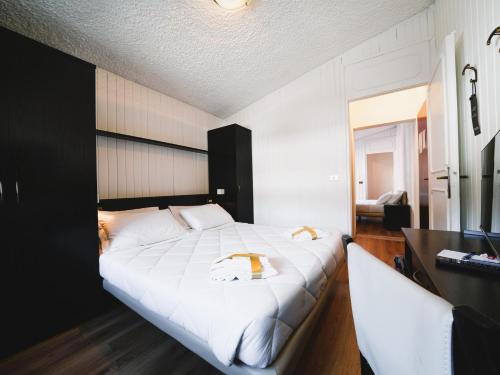a bedroom with a large white bed and a desk at Hotel Arlecchino - Dada Hotels in Madesimo