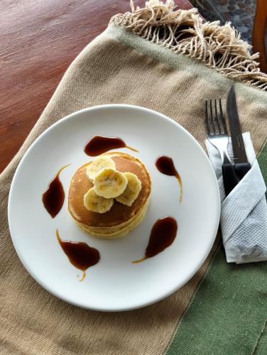 a white plate with pancakes with bananas and syrup at Arirang Sea View Homestay in Senggigi 
