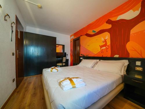 a bedroom with a large bed with a painting on the wall at Hotel Arlecchino - Dada Hotels in Madesimo