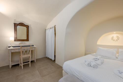 a bedroom with a bed and a desk and a mirror at Oia Mare Villas in Oia