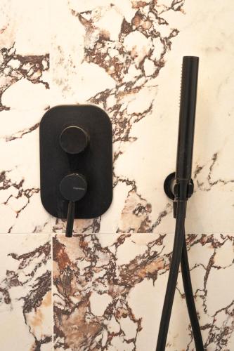 a black electrical outlet on a wall next to a tripod at NoMad Guest House in La Spezia