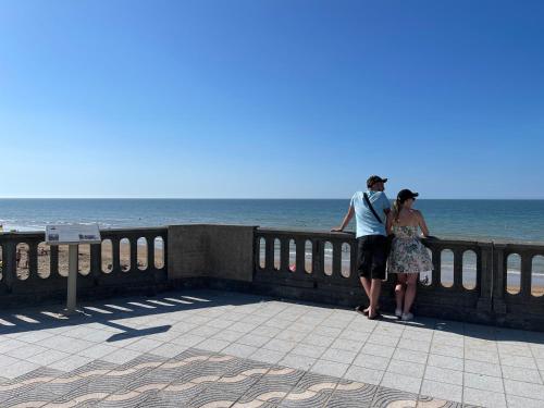 a man and woman standing on a wall near the ocean at Cabourg plage à 200m plage in Cabourg