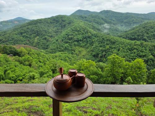 two tea pots sitting on a ledge overlooking a mountain at บ้านไร่ไอดอย in Phrae
