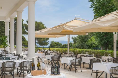 a restaurant with white tables and chairs and umbrellas at Boutique Hotel Esplanade - Adults only in Crikvenica