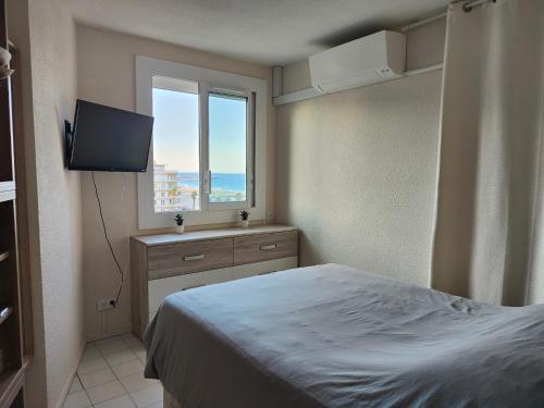 une chambre avec un lit, une télévision et une fenêtre dans l'établissement Front de Mer idéal classé 3 étoiles, à Canet