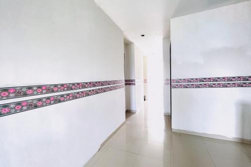 a hallway with white walls and pink flowers on the wall at RedDoorz at STM Suite Medan Amplas in Medan