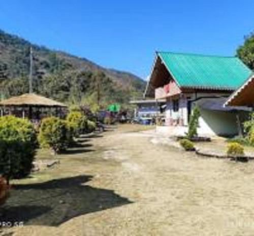 a building with a green roof next to a road at Yakthumba Tabakoshi Offbeat Homestay By StayApart in Mirik