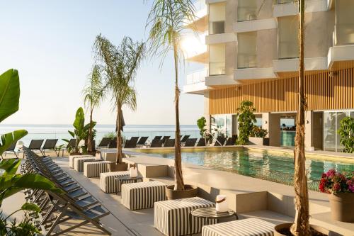 a hotel pool with chaise lounge chairs and palm trees at INNSiDE by Meliá Alicante Porta Maris in Alicante