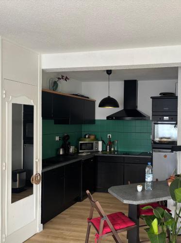 une cuisine avec des armoires noires et une table dans l'établissement Appartement avec jardin à 2 pas du lac, à Aix-les-Bains