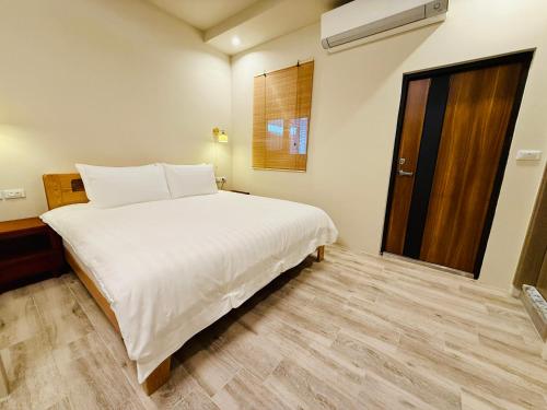 a bedroom with a large white bed and a window at 芊禹民宿 - 走路就到鐵花村-微光集-觀光夜市 - in Taitung City