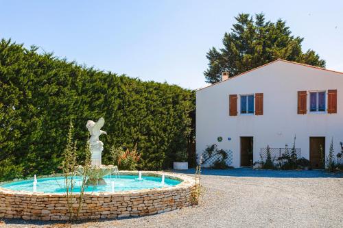 une maison avec une fontaine en face d'un bâtiment dans l'établissement Gîte Le Petit Sableau, à Marans