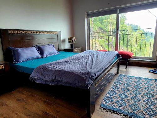 a bedroom with a bed and a large window at Haven Lodge Khaira Gali - Pine Ridge Residences #4 in Khaira Gali
